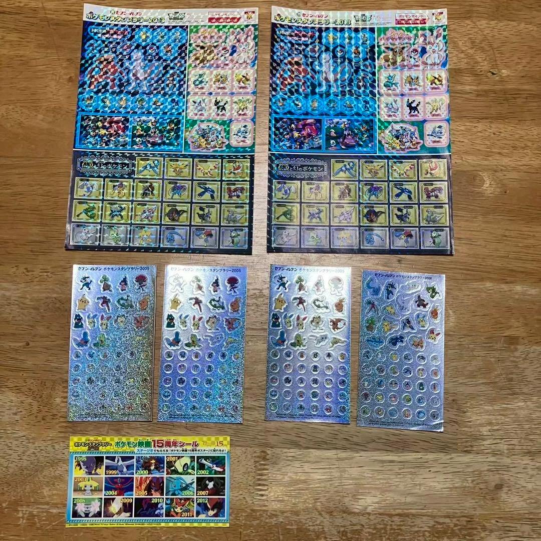 Multiple holographic Pokémon sticker sheets arranged on a wooden table, showing various small character stickers.