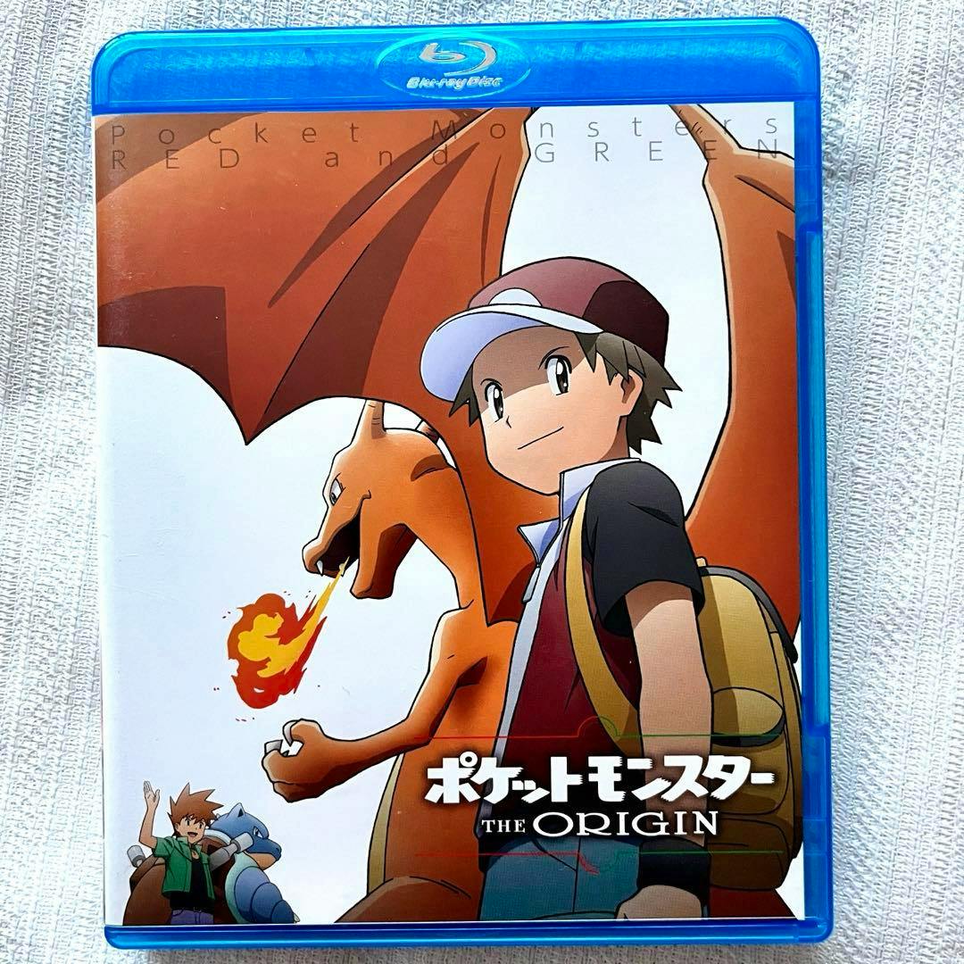 Front cover of the Blu-ray case for ポケットモンスター THE ORIGIN showing anime artwork of a trainer standing next to Charizard.