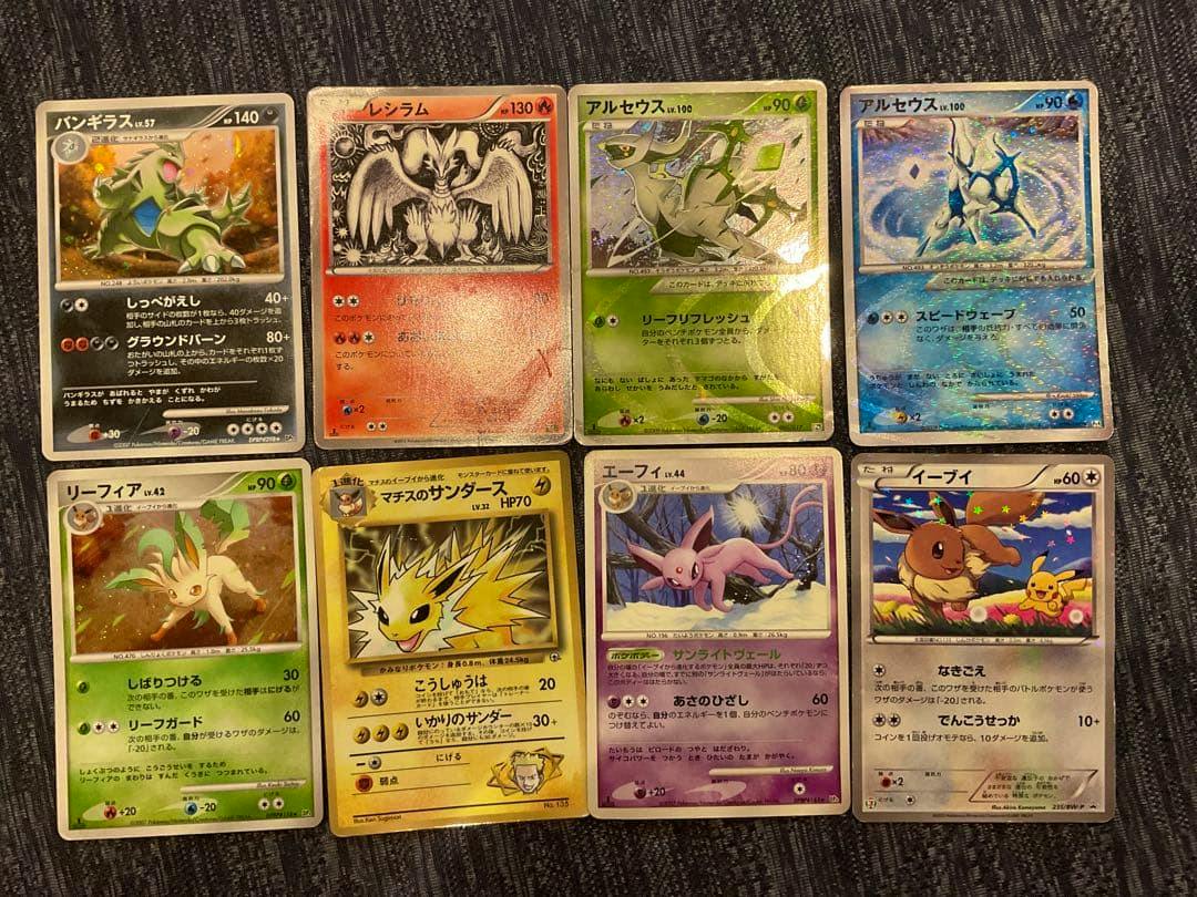 Pokémon trading cards laid out face-up on a dark fabric background, showing various card artworks and holo effects.