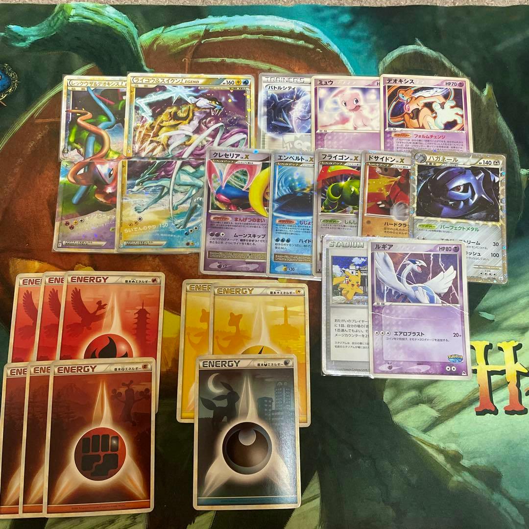 A spread of Pokémon trading cards and several energy cards displayed on a playmat.