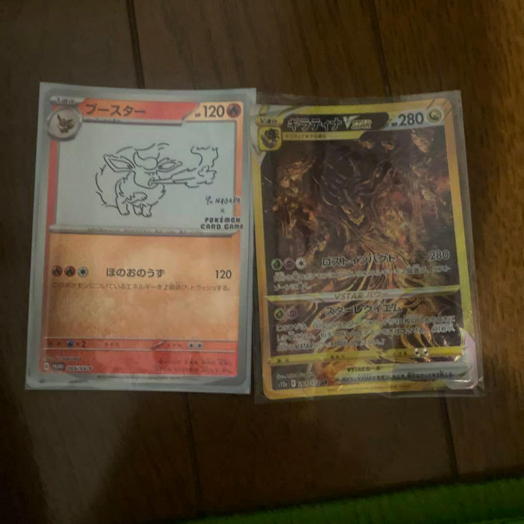 Two Pokémon trading cards in sleeves placed on a wooden floor, an orange-bordered card on the left and a holographic foil card on the right.