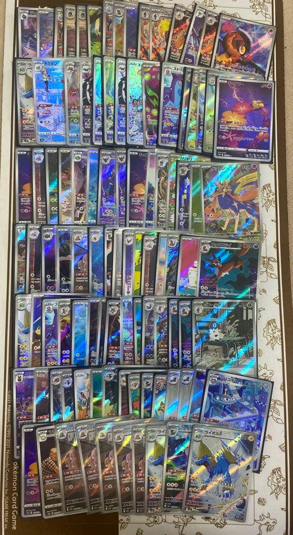 A photo of many holographic Pokémon trading cards (AR/CHR) laid out in rows on a flat surface.
