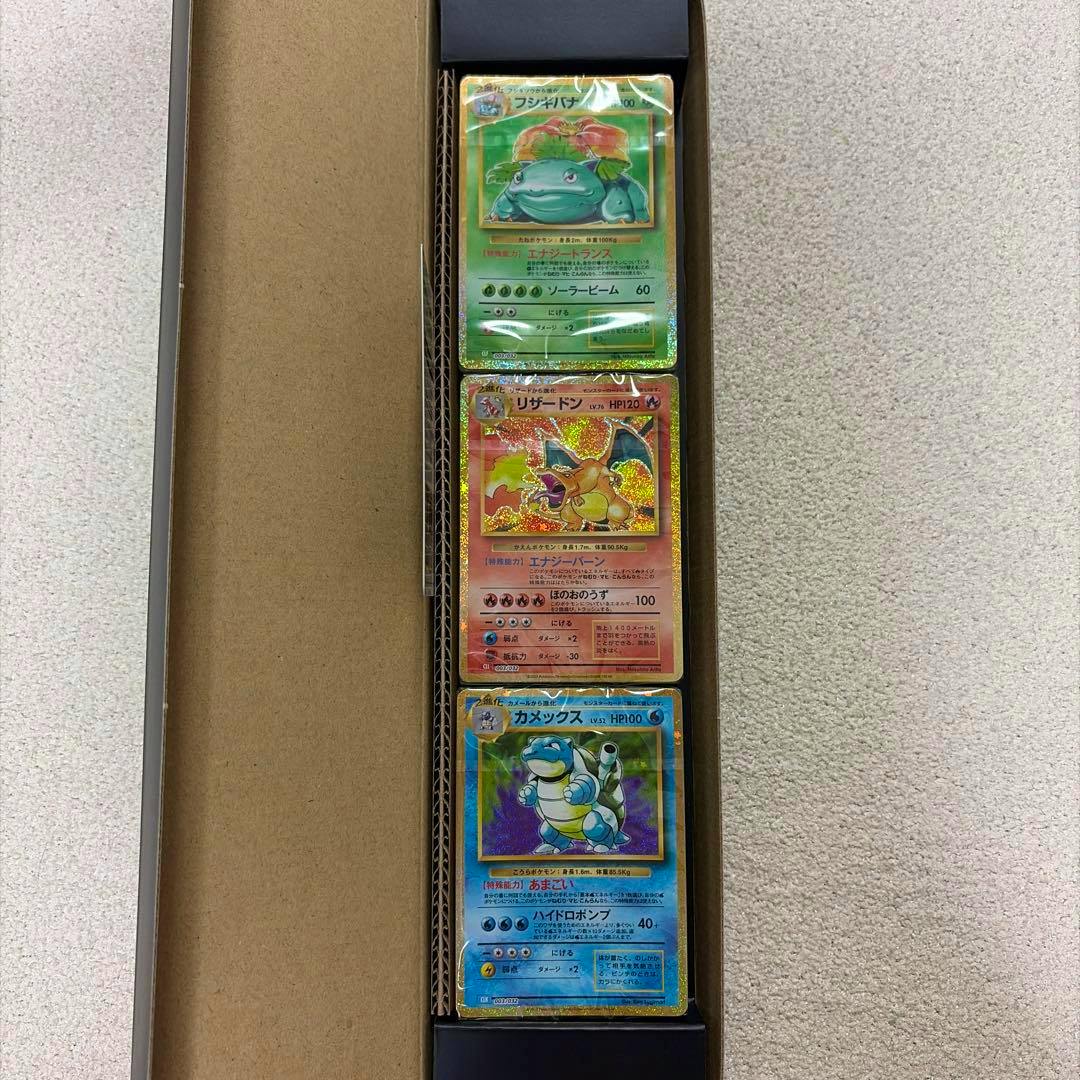 Three Pokémon cards labeled フシギバナ, リザードン, and カメックス stacked vertically inside a cardboard box.