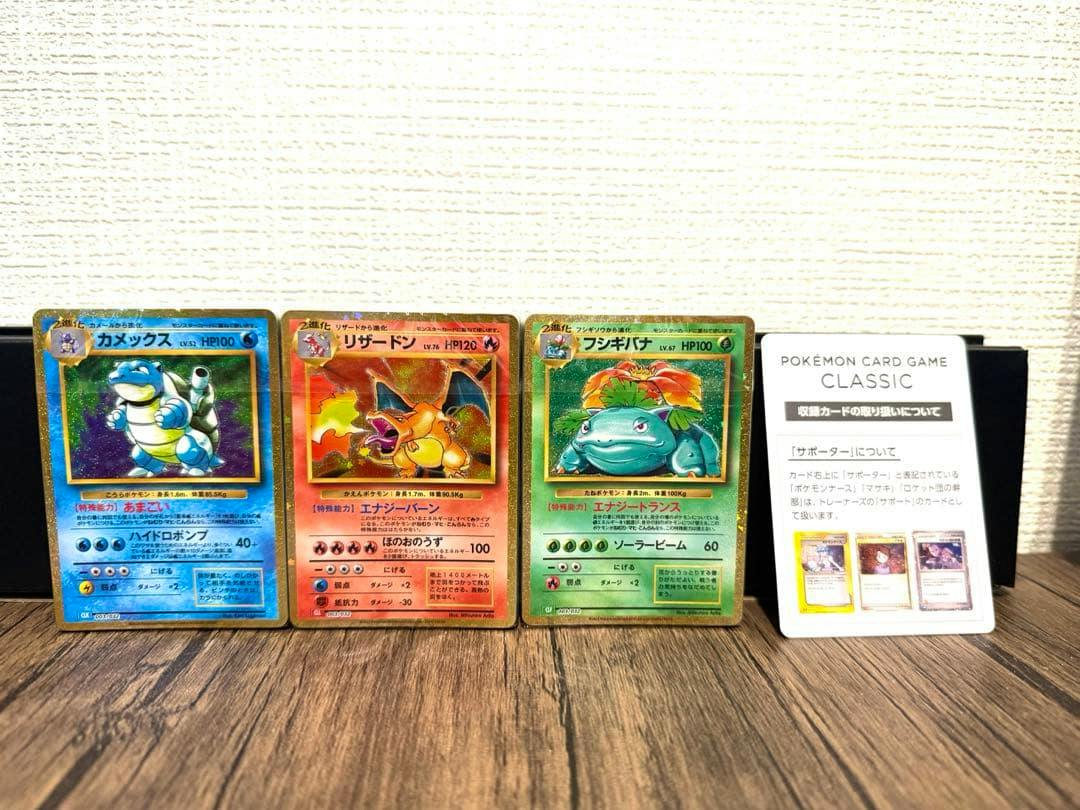 Three sealed Pokémon Card Game CLASSIC decks showing Blastoise, Charizard, and Venusaur artwork with a CLASSIC information card beside them on a wooden surface.