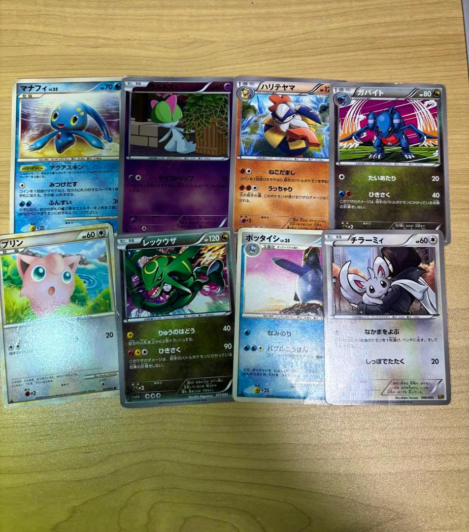 Seven Pokémon trading cards from a bulk set laid out on a wooden surface.