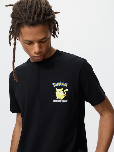 A black men's cotton Pokémon T-shirt with a small Pikachu graphic worn by a model.