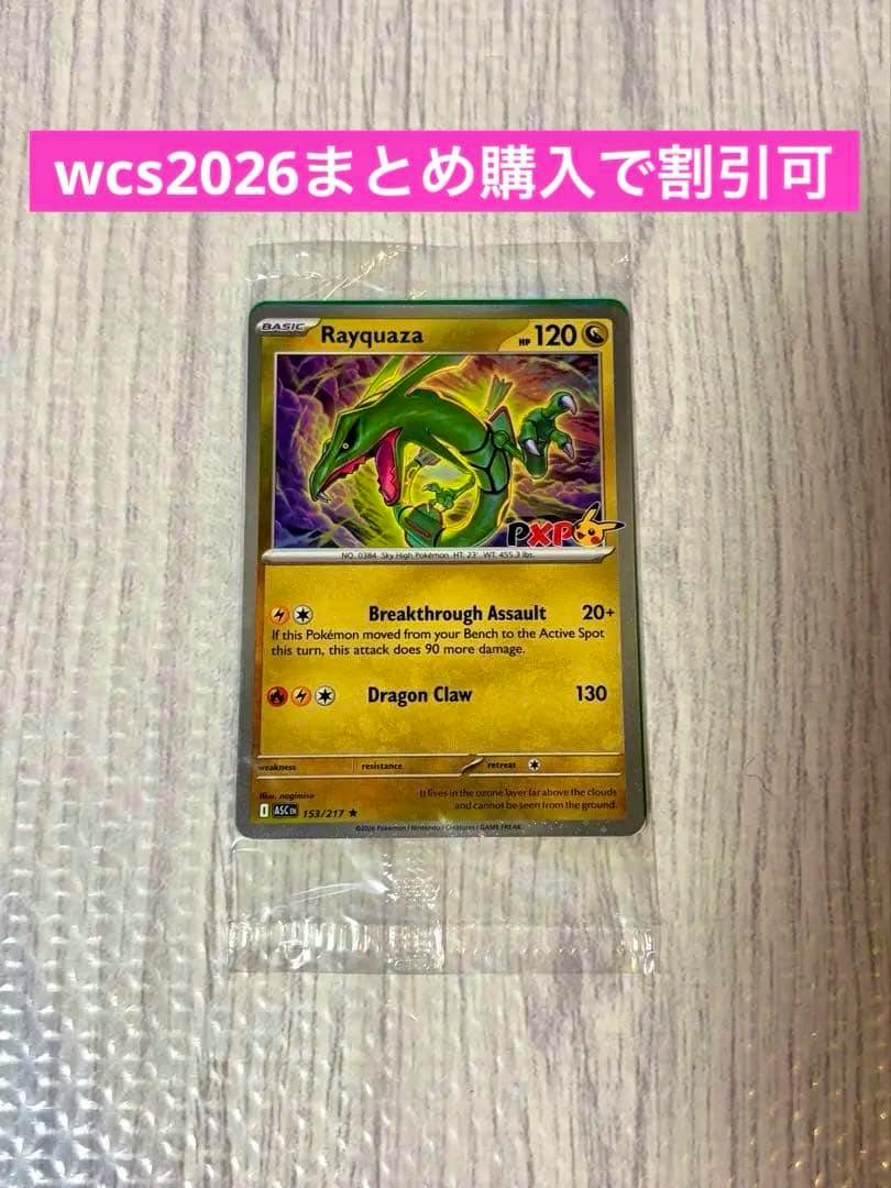 Front of the WCS2026 Rayquaza promo trading card in a plastic sleeve placed on a textured surface, with a pink banner visible at the top.