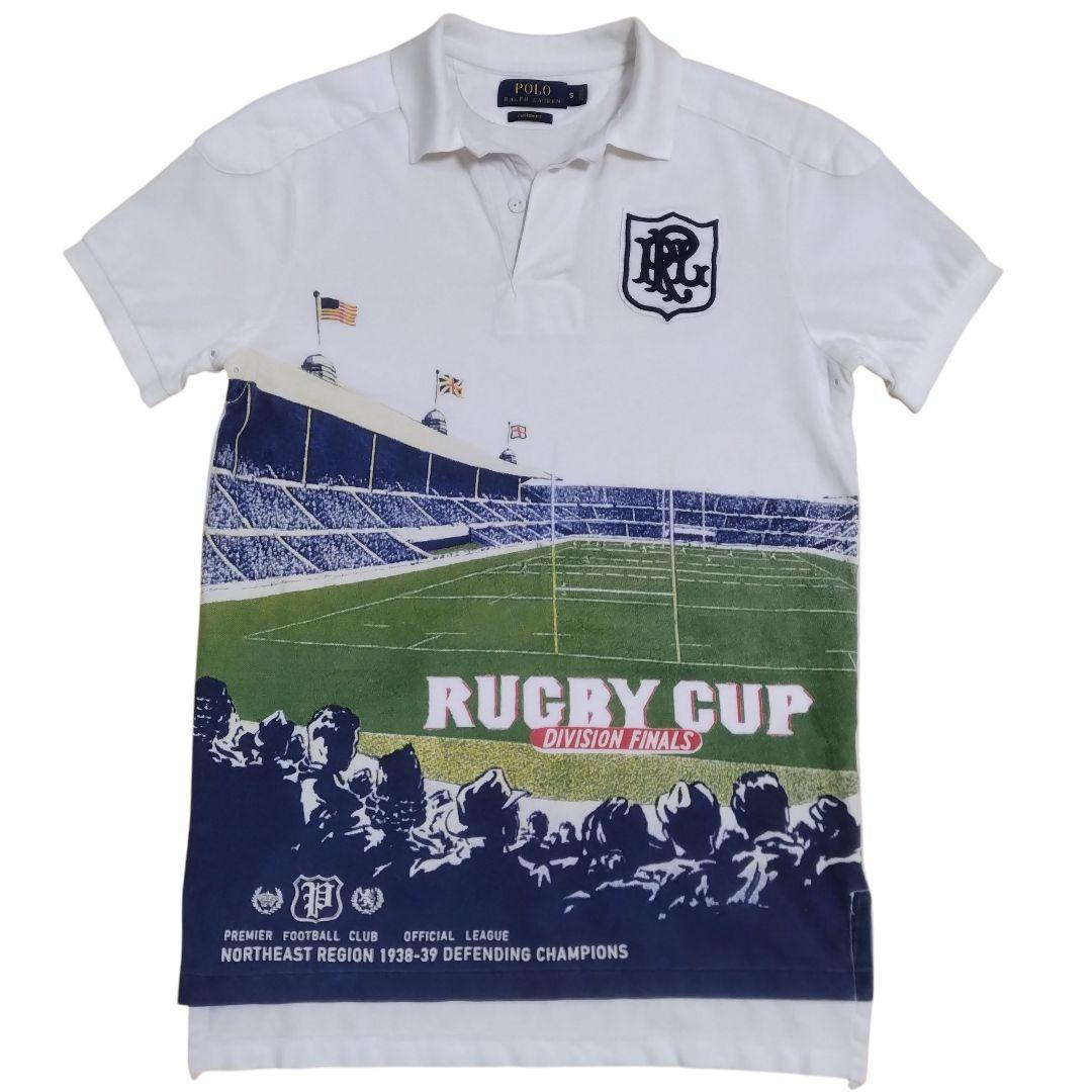 White short-sleeve Polo-style rugby shirt with a large green stadium "RUGBY CUP" graphic across the front and a chest crest.