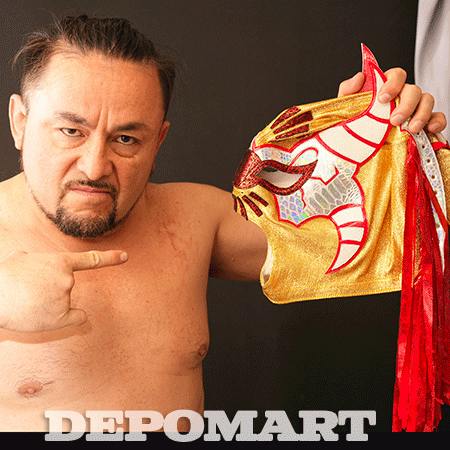 A shirtless man holds a gold and red pro wrestling mask against a dark background.