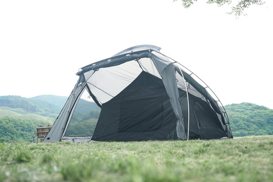 Exterior view of a polyester tent set up outdoors on grass with its front opening visible.