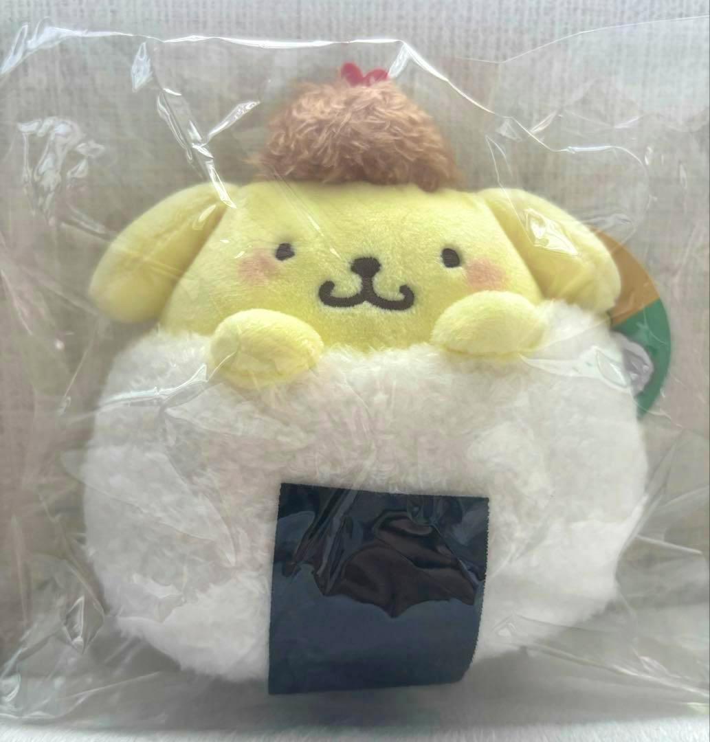 Pompompurin onigiri plush mascot in plastic packaging, showing the yellow character sitting on a white rice-ball plush with a black seaweed square.