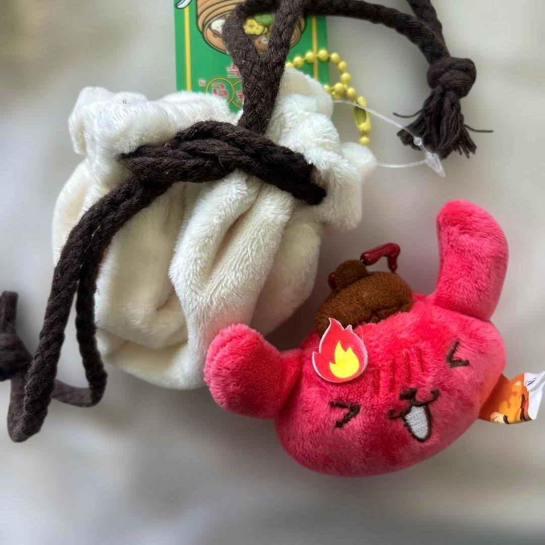 Pink Pom Pom Purin plush mascot keychain shown next to a small white drawstring pouch.