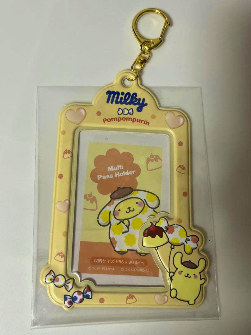 Yellow Pompompurin Milky multi pass holder keychain with a gold clasp and decorative candies, shown in plastic packaging.