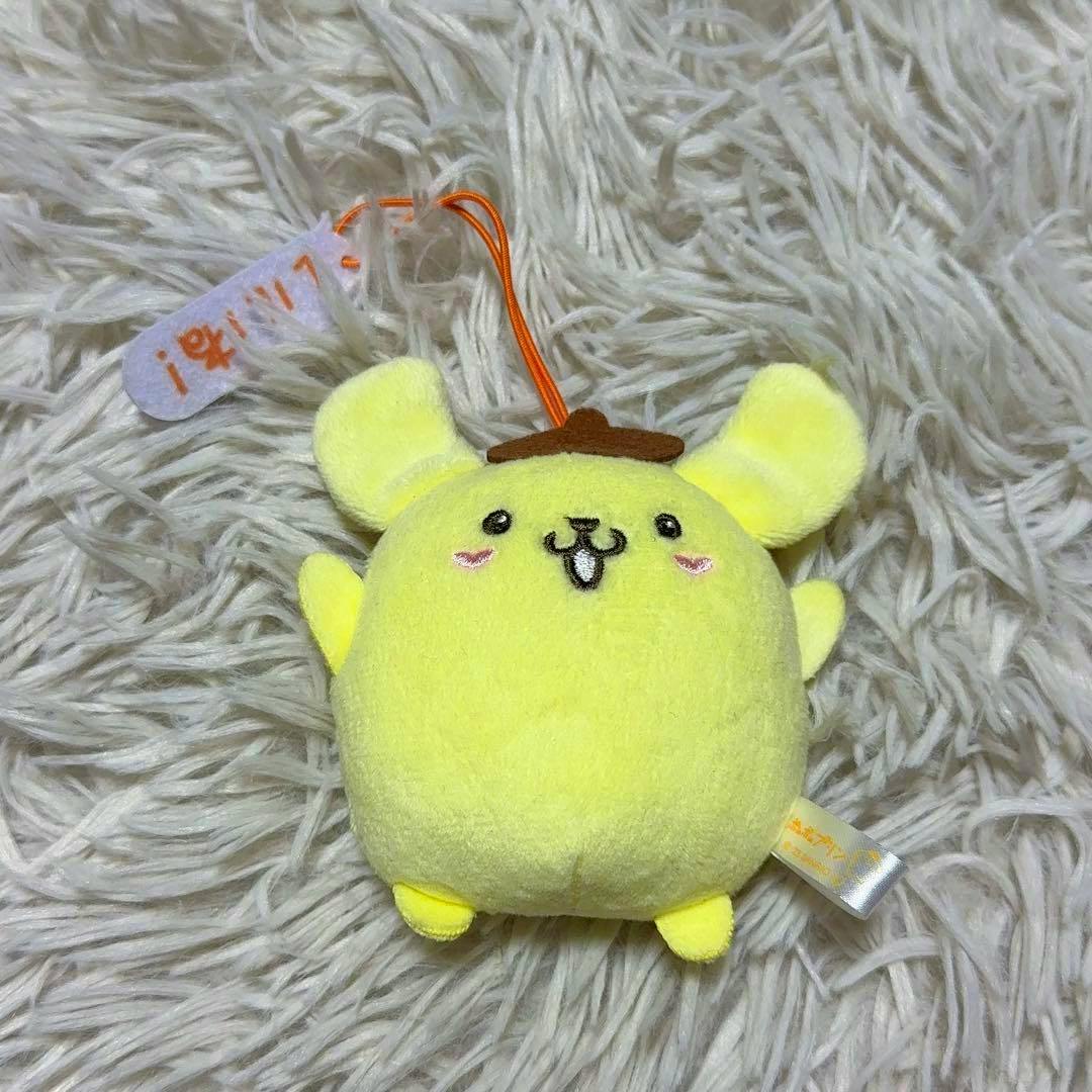 A small yellow Pompompurin plush mascot with a brown beret on a shaggy white background.