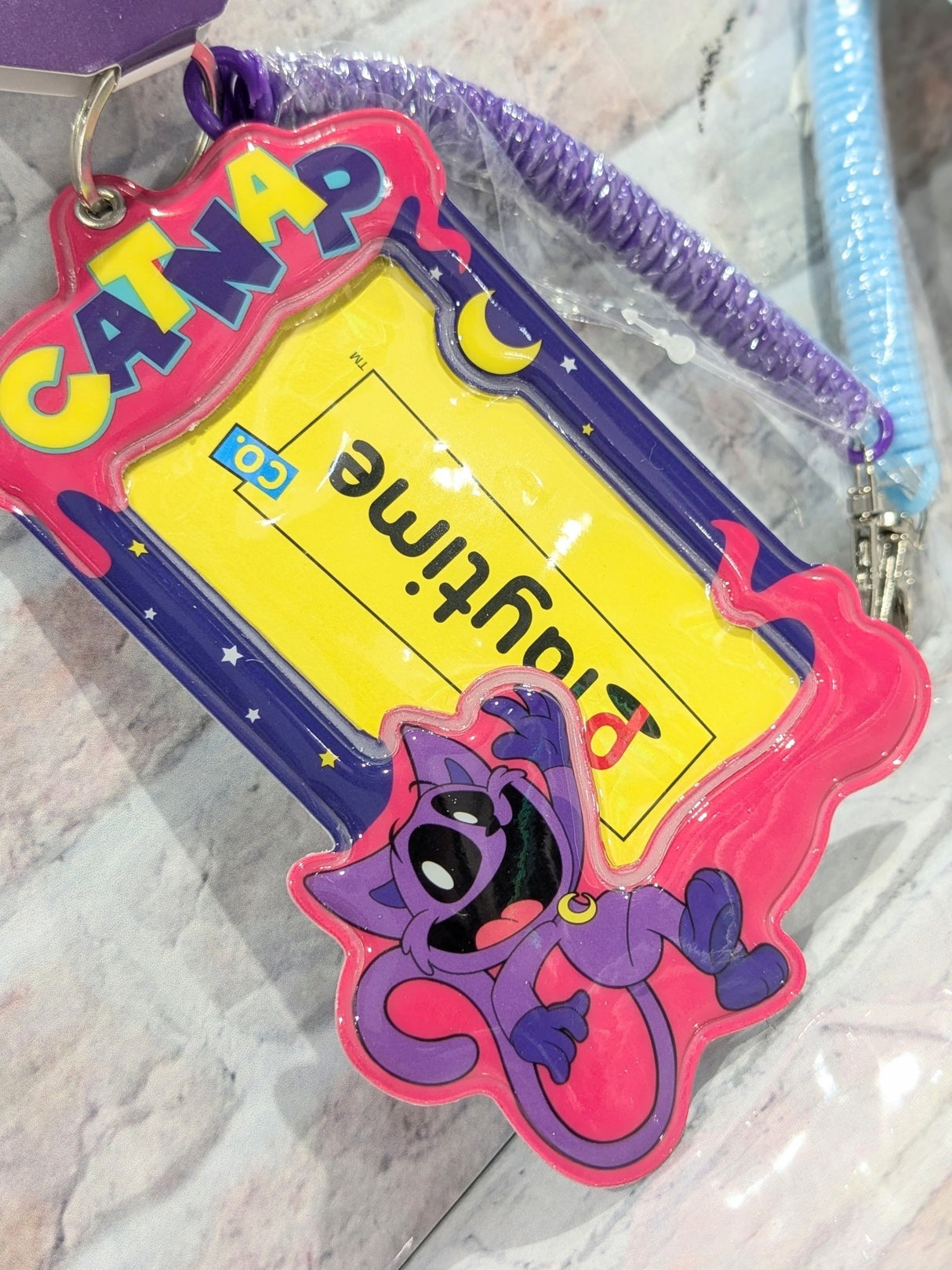 Purple and pink Poppy Playtime PVC pass case with a cartoon character, a clear ID window showing a playtime insert, and a purple coiled strap.