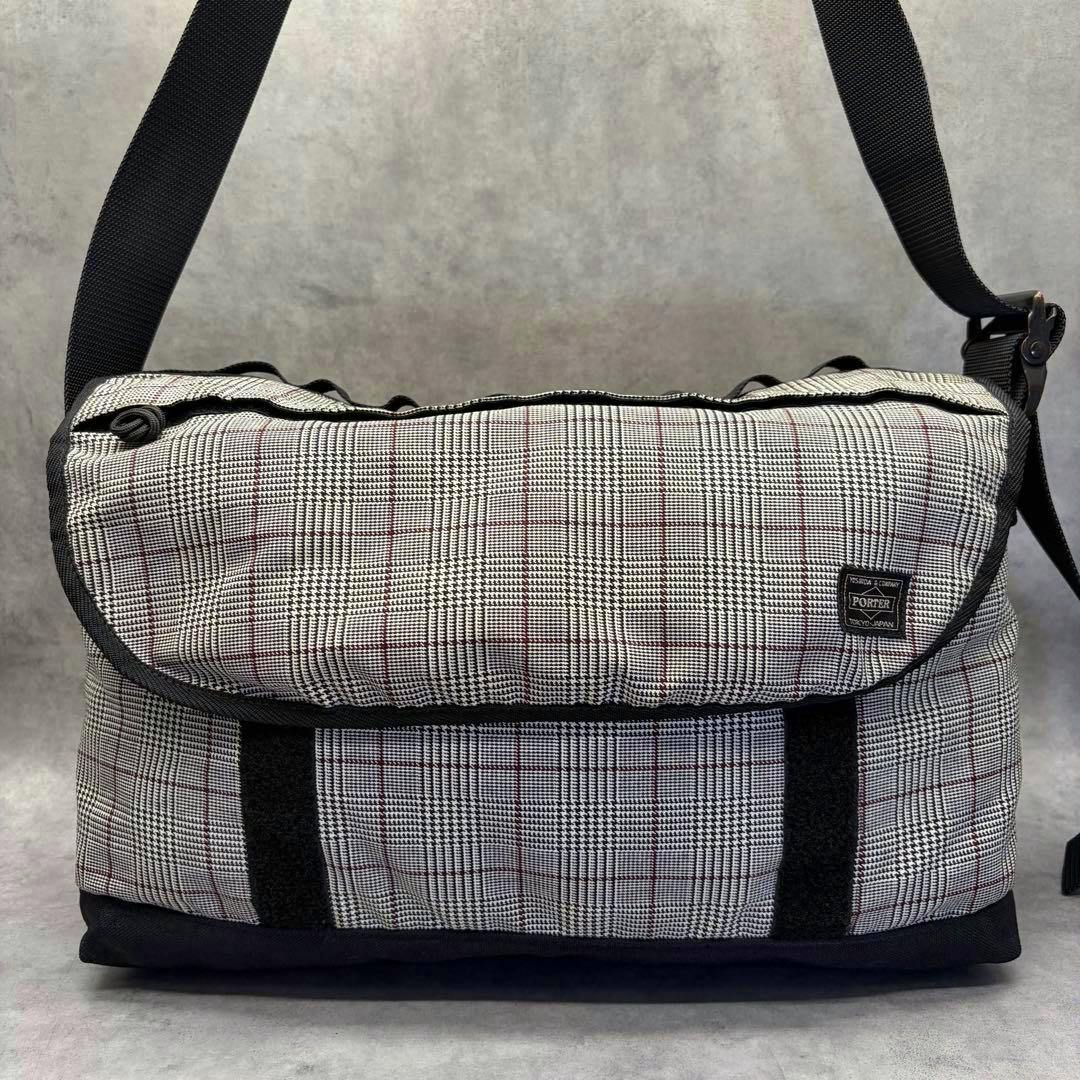 Front view of the PORTER×MEN’S MELROSE glen check messenger bag showing the patterned flap, black strap, and PORTER label.