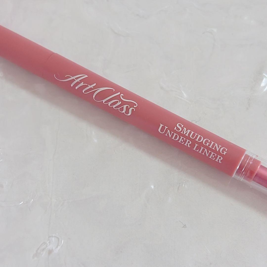 Close-up of a pink "Smudging Under Liner" eyeliner pencil with "ArtClass" printed on the barrel.