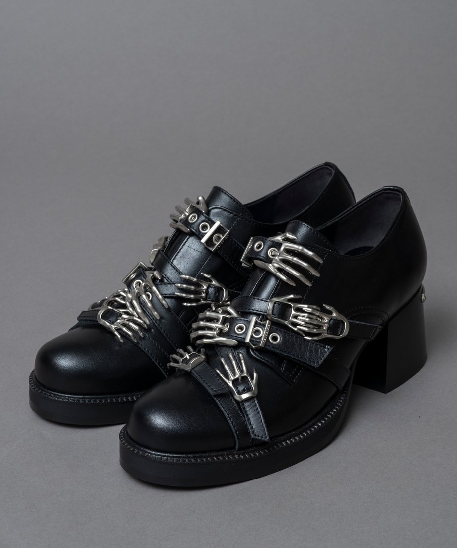 Black leather loafers with multiple metal buckles displayed on a gray background.
