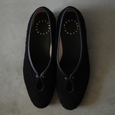 Top-down photo of a pair of black Tear Pumps placed side by side on a gray surface.
