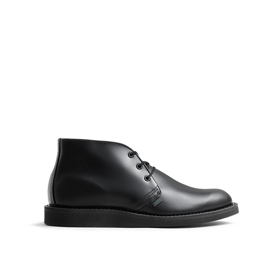 Side profile of a black leather Postman Chukka shoe on a black background.
