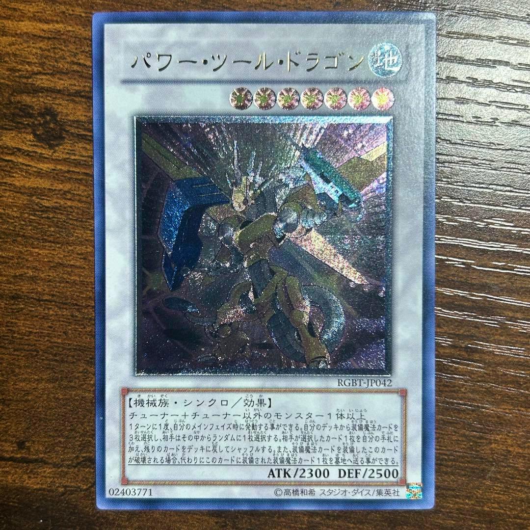Photograph of the Japanese Yu-Gi-Oh trading card パワー・ツール・ドラゴン showing the card front, artwork, and ATK/DEF text.