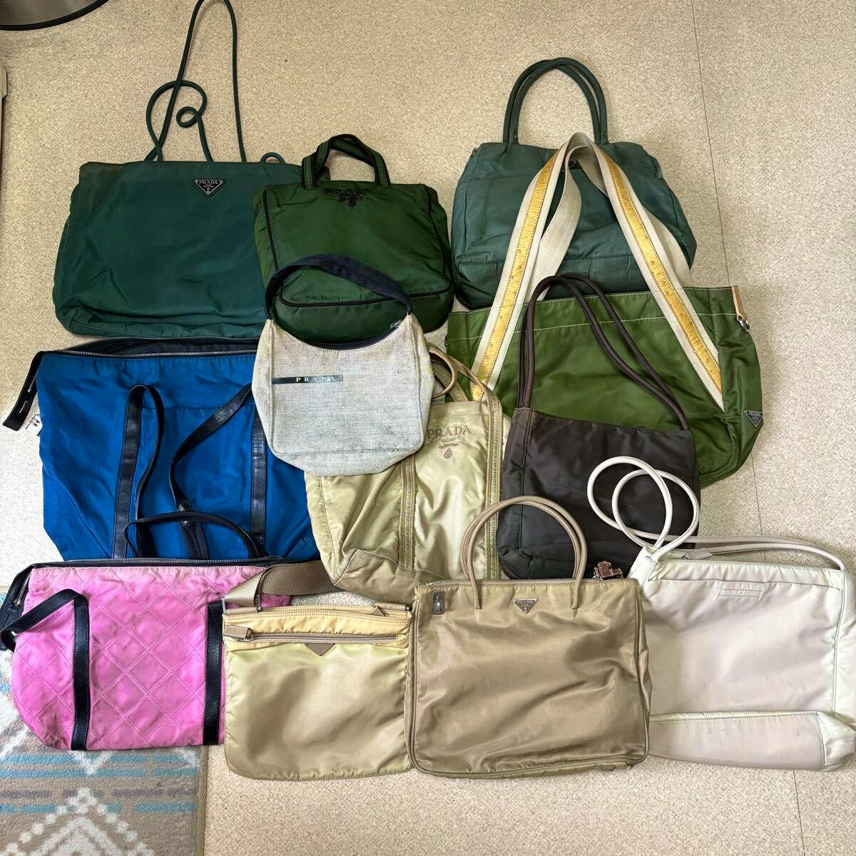Several PRADA bags and totes in various colors arranged on a floor.