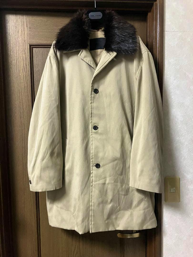 Beige men's half coat with a dark beaver-fur collar hanging on a door, front button closure visible.