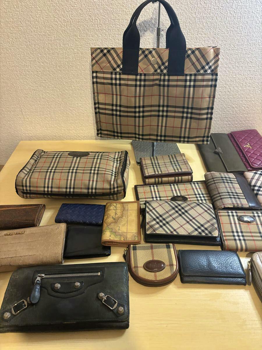 Multiple wallets and small pouches arranged on a table with a beige checked tote bag displayed in the background.