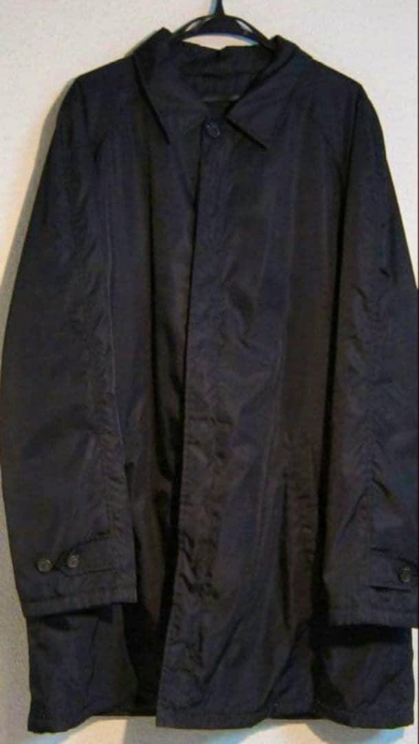 PRADA Archive nylon trench coat hanging on a hanger against a light wall.
