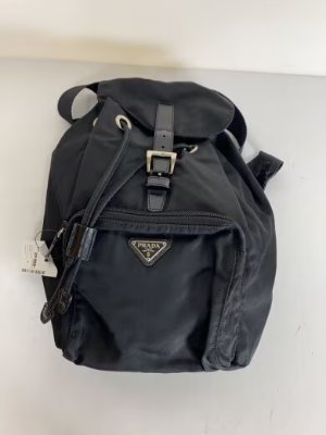 Front view of a black Prada nylon backpack on a light background.