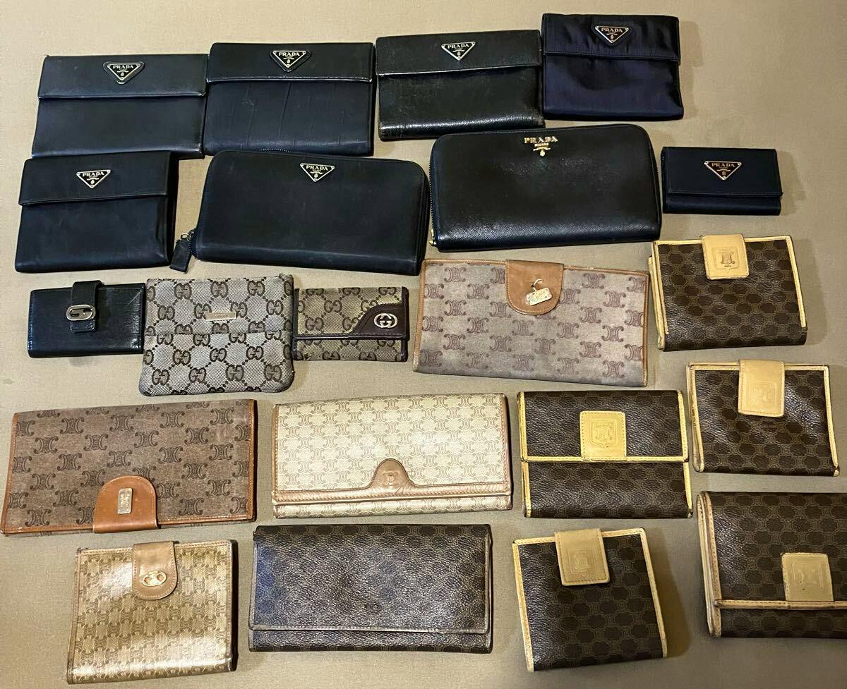 Top-down photo of assorted branded wallets and key cases, including several black Prada pieces, arranged on a flat surface.