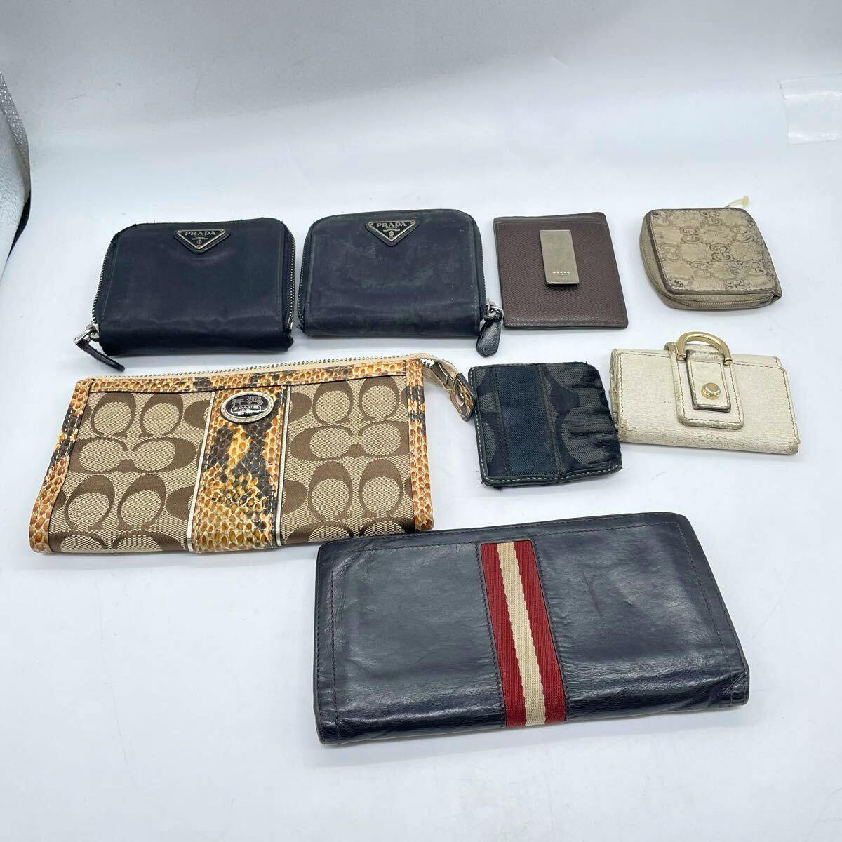 Eight assorted branded wallets and small cases arranged on a white background.