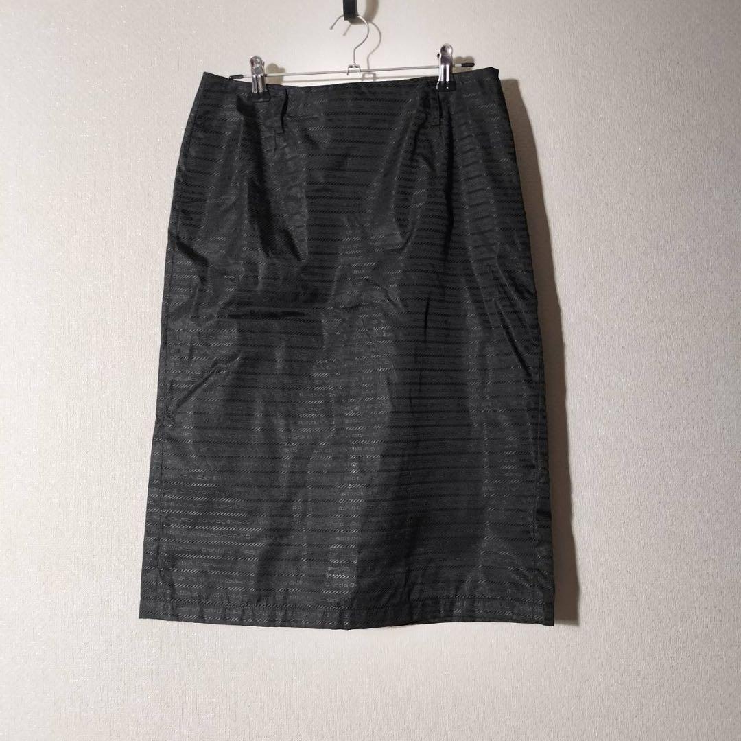 Prada black nylon knee-length women's skirt with subtle horizontal textured stripes hanging on a hanger against a wall.