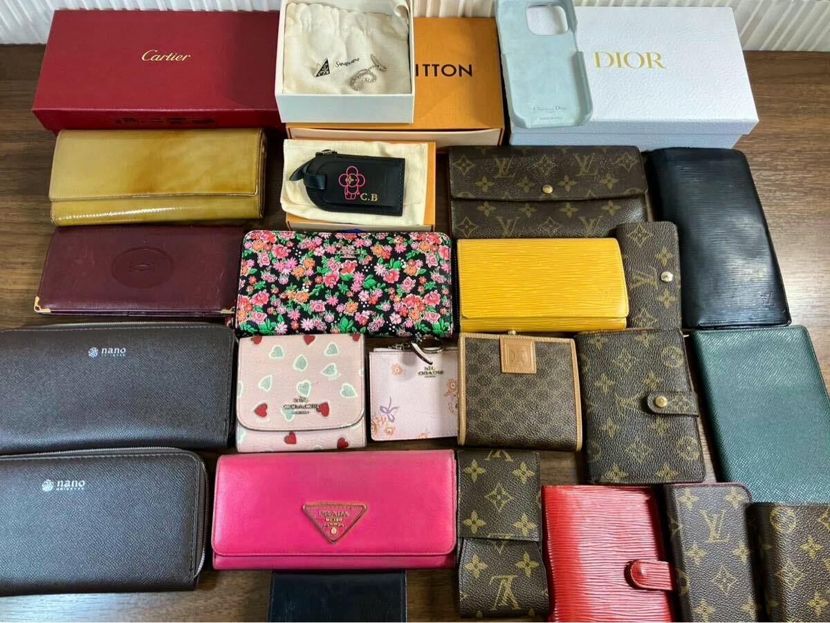 Multiple wallets and luxury brand boxes, including Louis Vuitton monogram wallets, arranged on a wooden table.