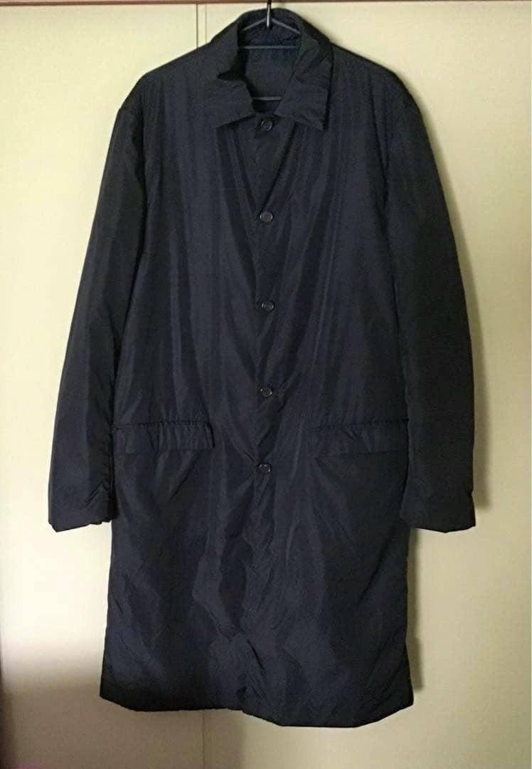 Front view of a men's long dark nylon coat hanging on a hanger against a plain background.