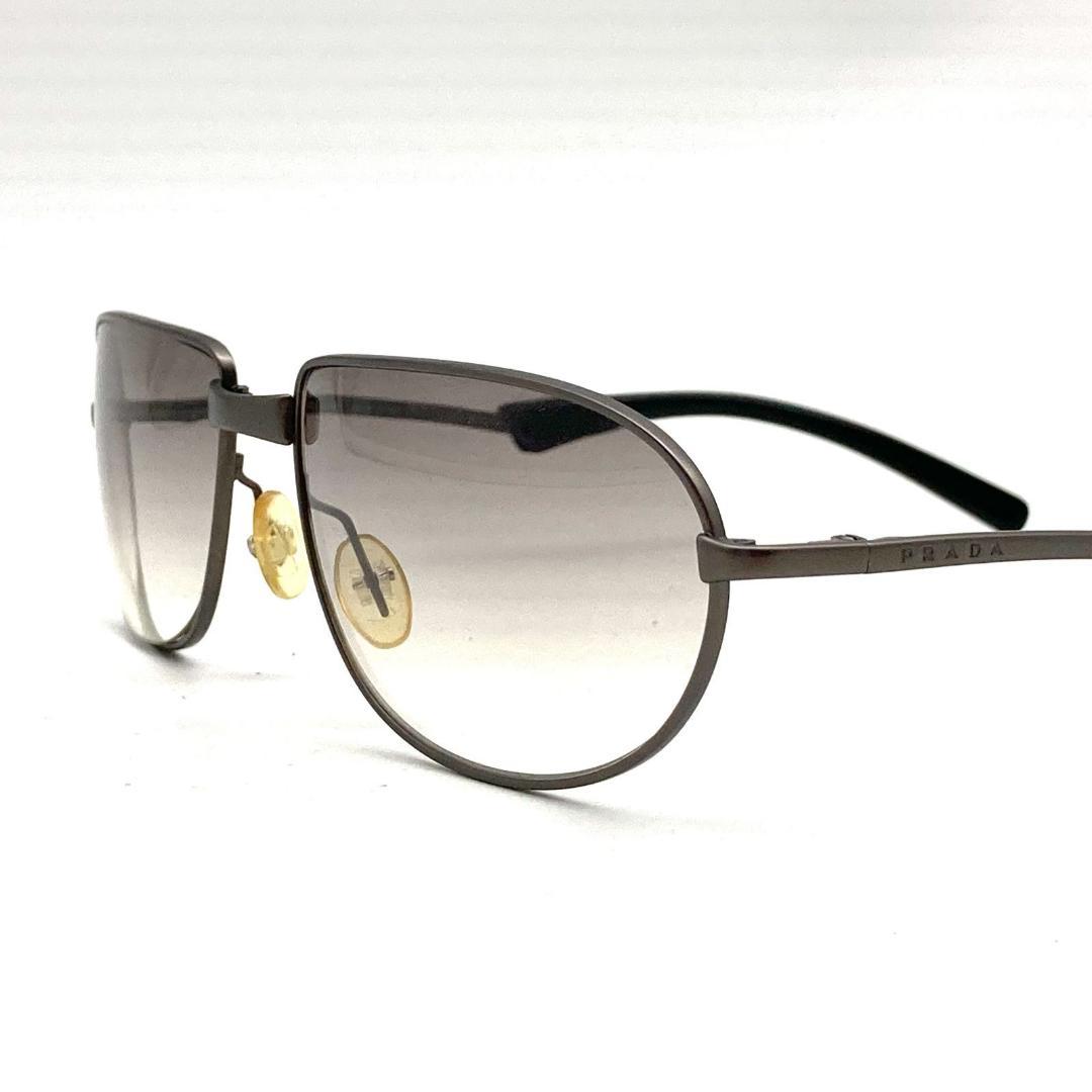 Close-up photo of metal Prada sunglasses with silver frame, gradient gray lenses, and black temple tips.