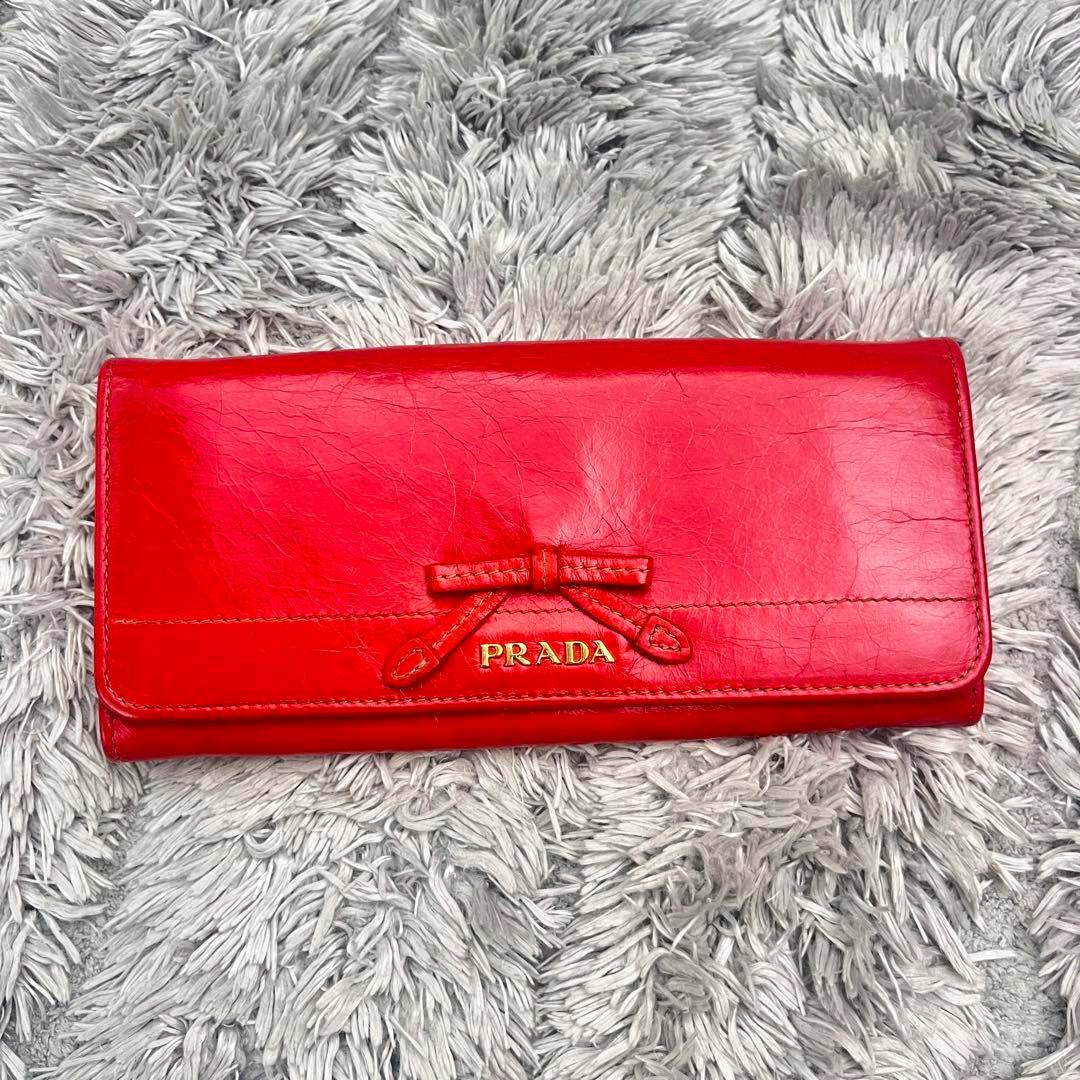 Red Prada long leather wallet with a small front bow and gold PRADA logo.