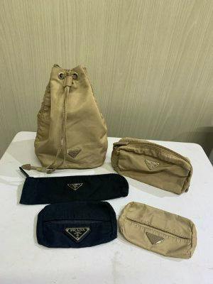Several beige and black Prada nylon pouches, including a beige drawstring pouch, displayed on a white surface.