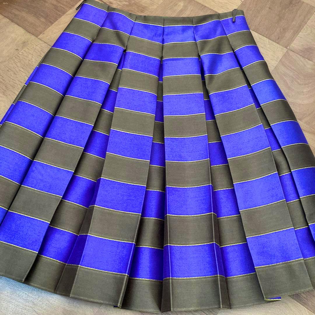 Pleated silk Prada skirt with wide alternating blue and olive horizontal stripes laid flat on a wooden floor.