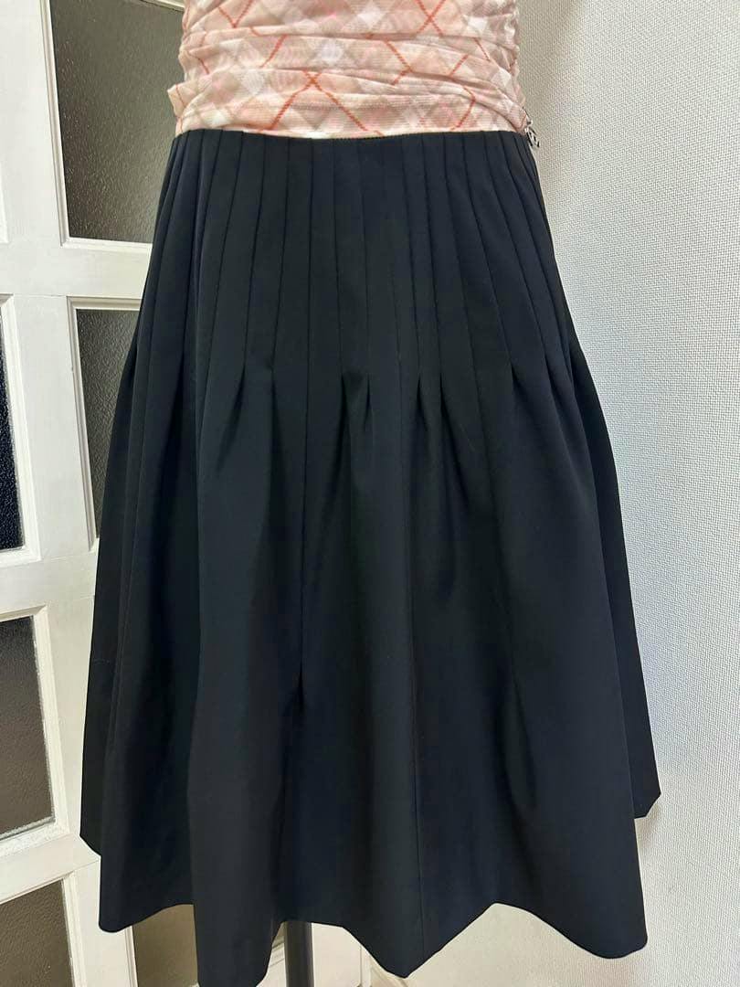 Front view of the PRADA black pleated skirt displayed on a dress form.