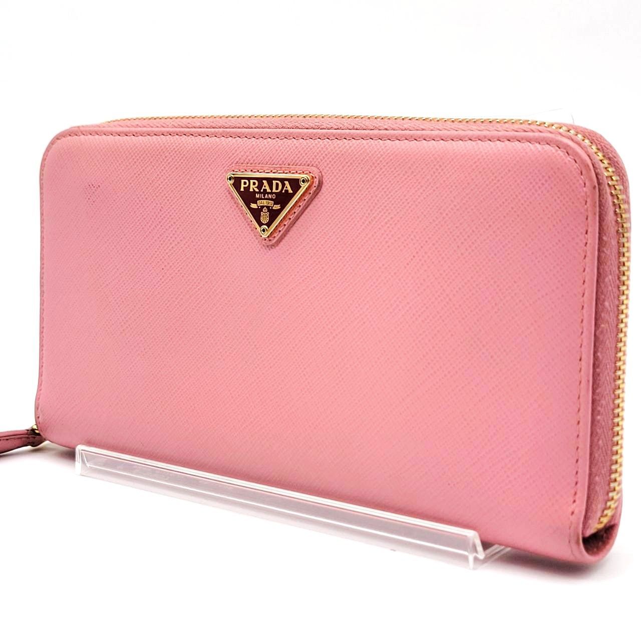 Pink Prada long zip-around wallet with a gold triangular logo shown on a clear display stand.