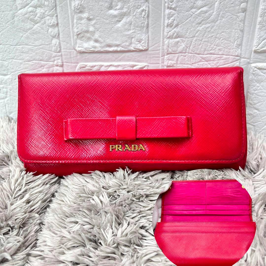 Red Prada long patent leather wallet with a front bow and gold PRADA logo, with an inset showing the interior.