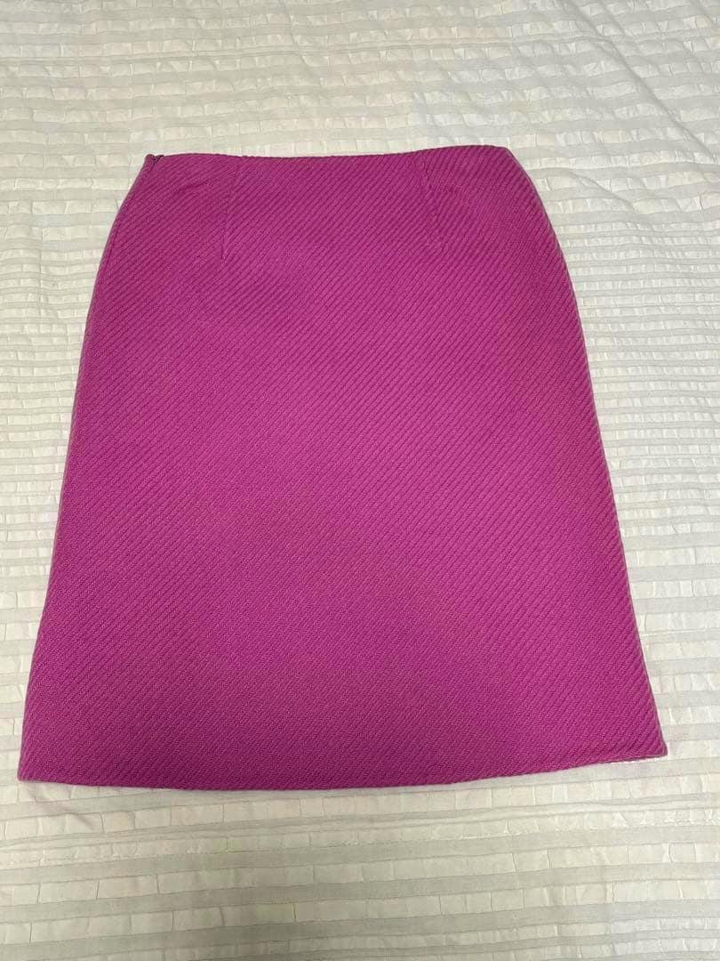 A pink skirt laid flat on a white textured surface, showing the front of the skirt.