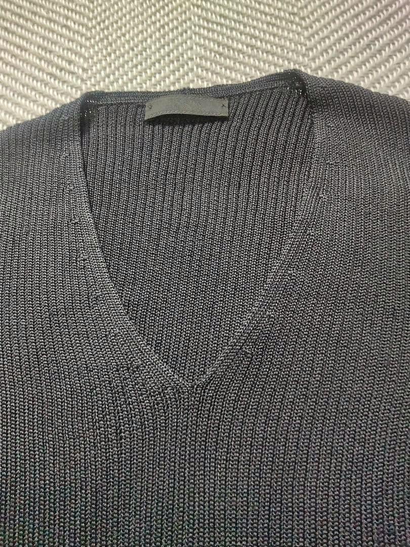 Close-up of a black ribbed V-neck knit sweater showing the neckline and upper chest.