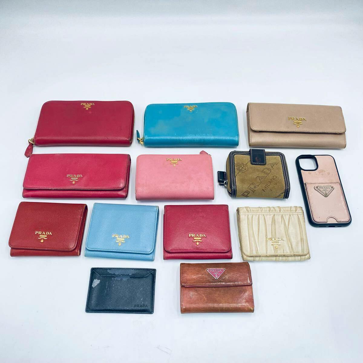 Thirteen PRADA wallets and a smartphone case arranged on a white background.