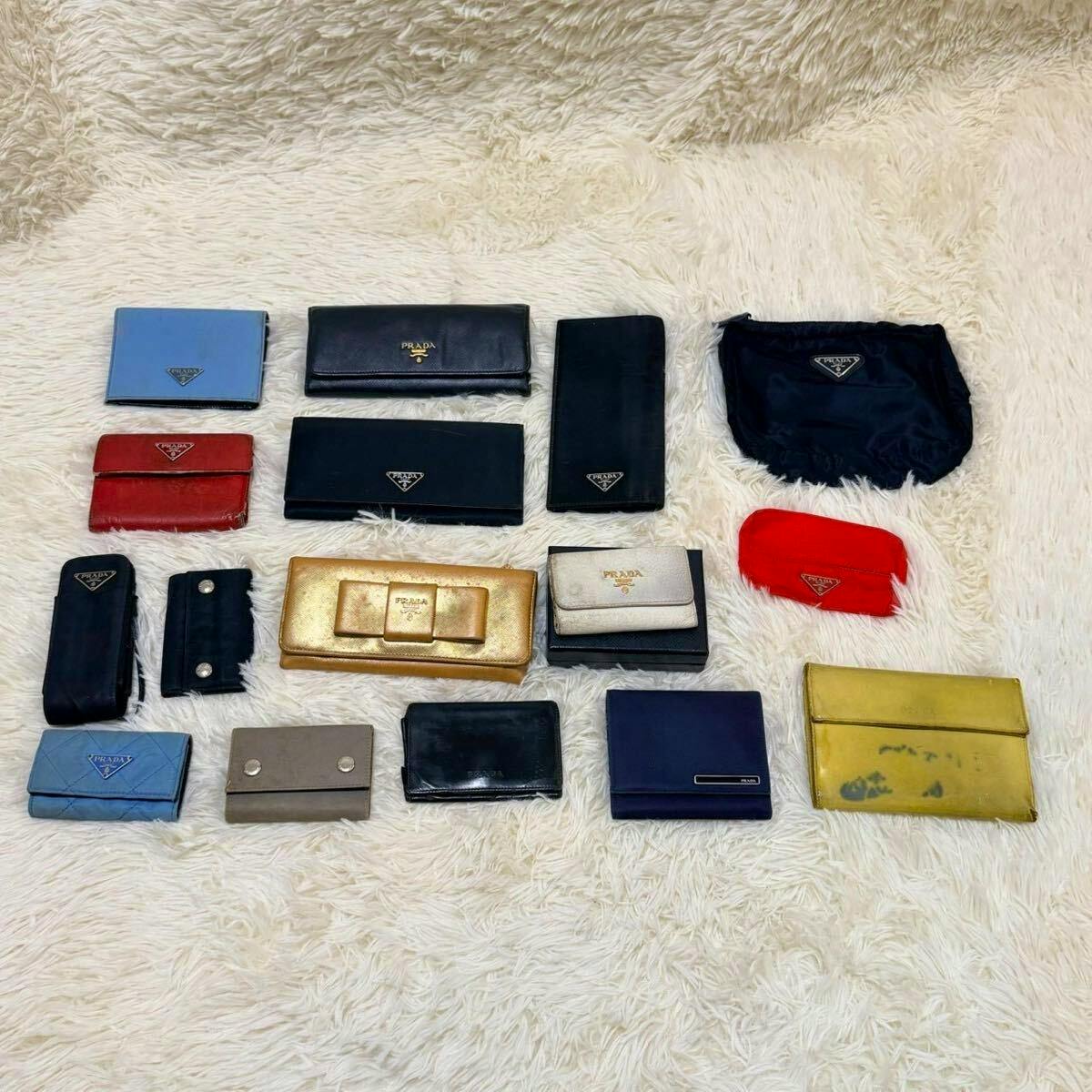 Multiple PRADA wallets, key cases, and pouches arranged on a white shag rug.