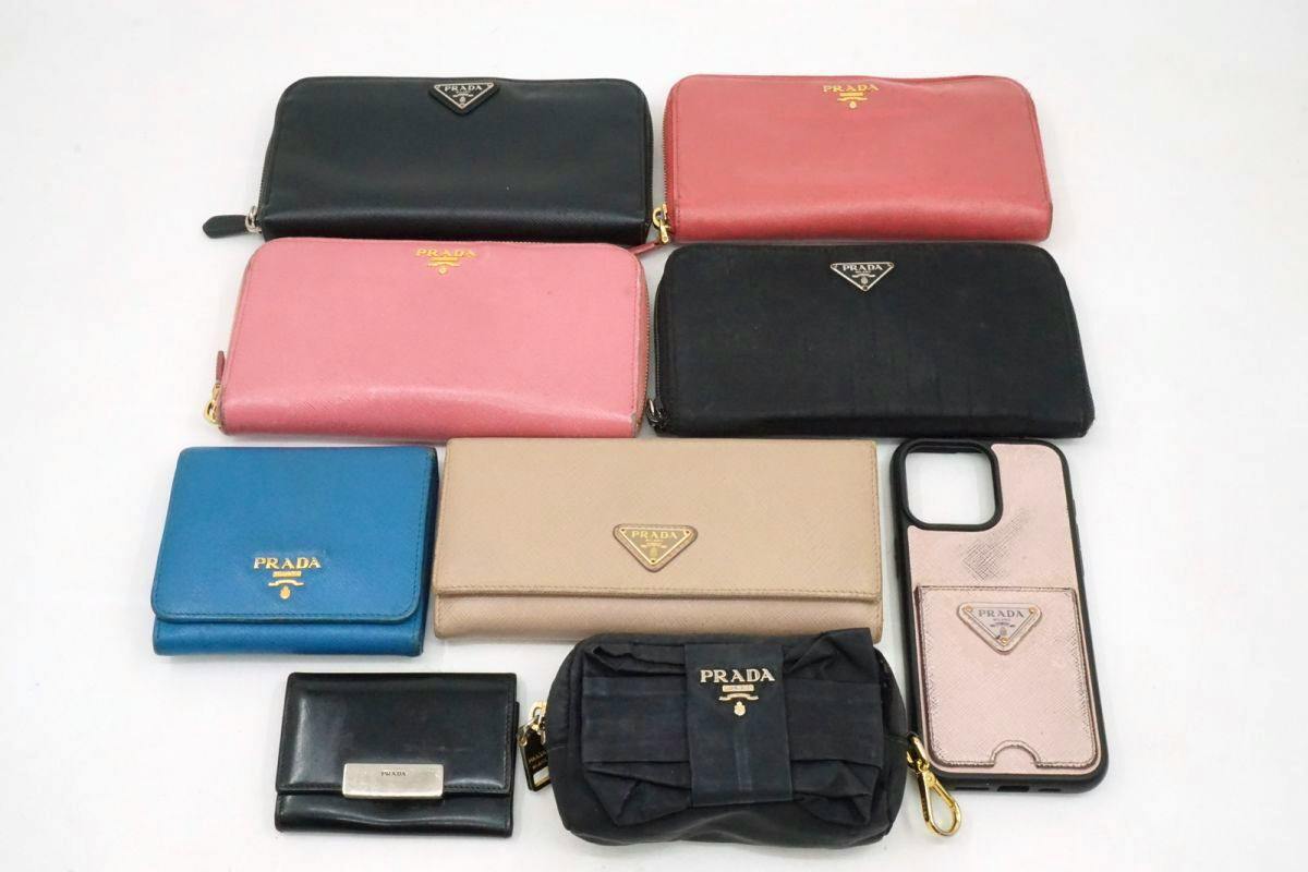 Nine PRADA wallets and accessories (wallets, pouches, key case, iPhone case) laid out on a white background.