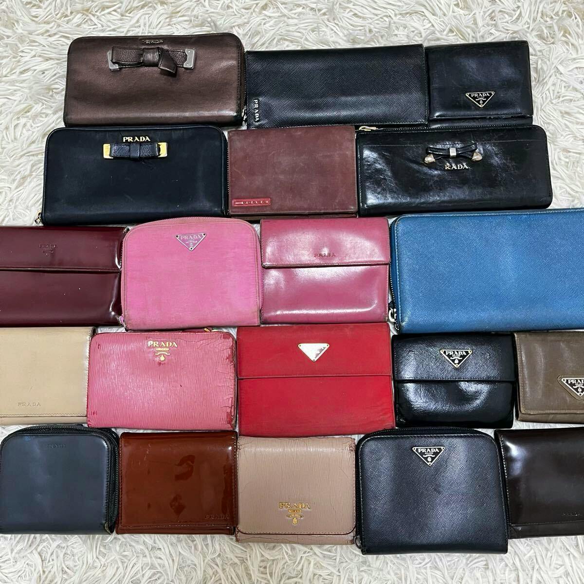 Multiple PRADA wallets in various colors and styles arranged on a white shag rug.