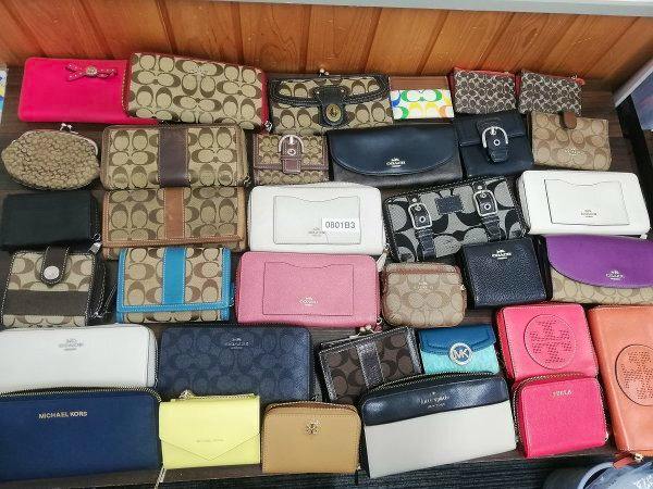 Many assorted wallets and coin purses arranged in rows on a flat surface.