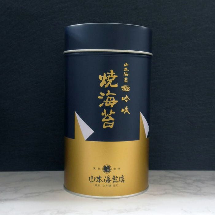 A dark blue and gold cylindrical tin package labeled in Japanese for roasted seaweed (dried seaweed).